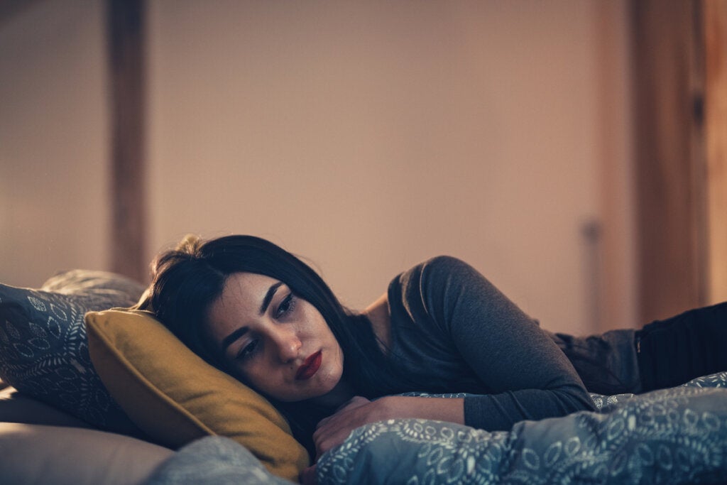 Mujer triste en la cama evidenciando la emotividad negativa en la depresión