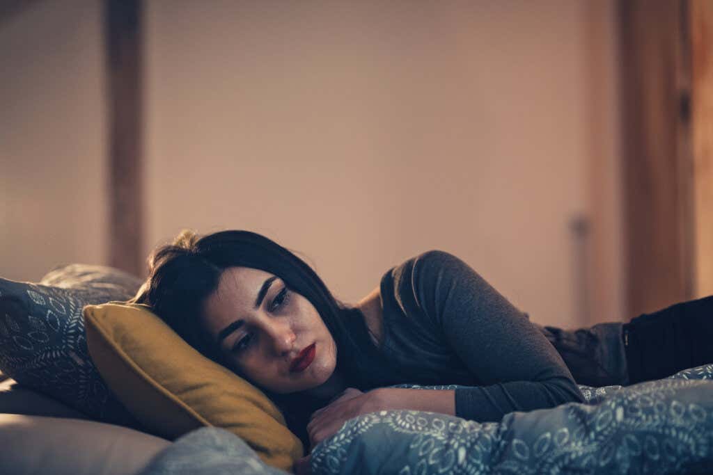 Mujer triste en la cama pensando en cuando una amistad nos traiciona con nuestra pareja