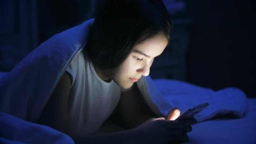 Meisje in bed op haar mobiel