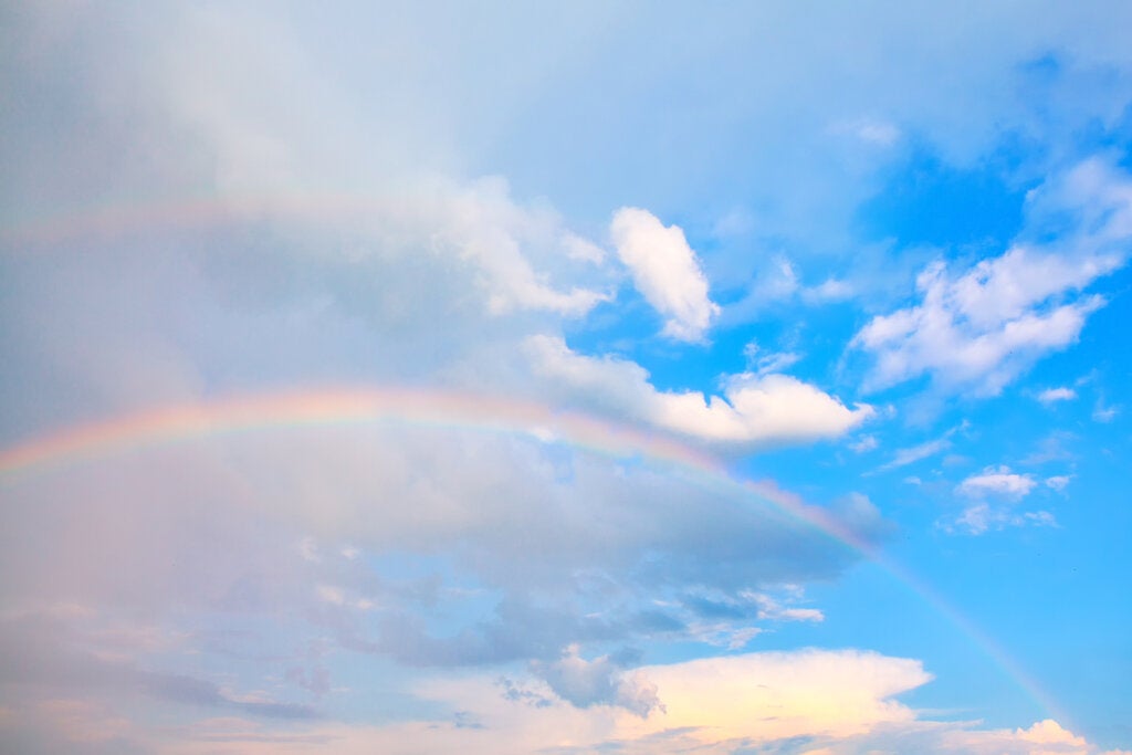 Regnbue mellom en regnfull himmel og en klar himmel.