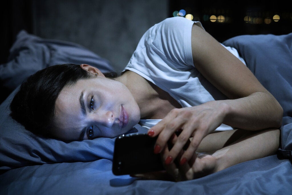 Mujer mirando el móvil por la noche pensando en enamorarse desde la distancia