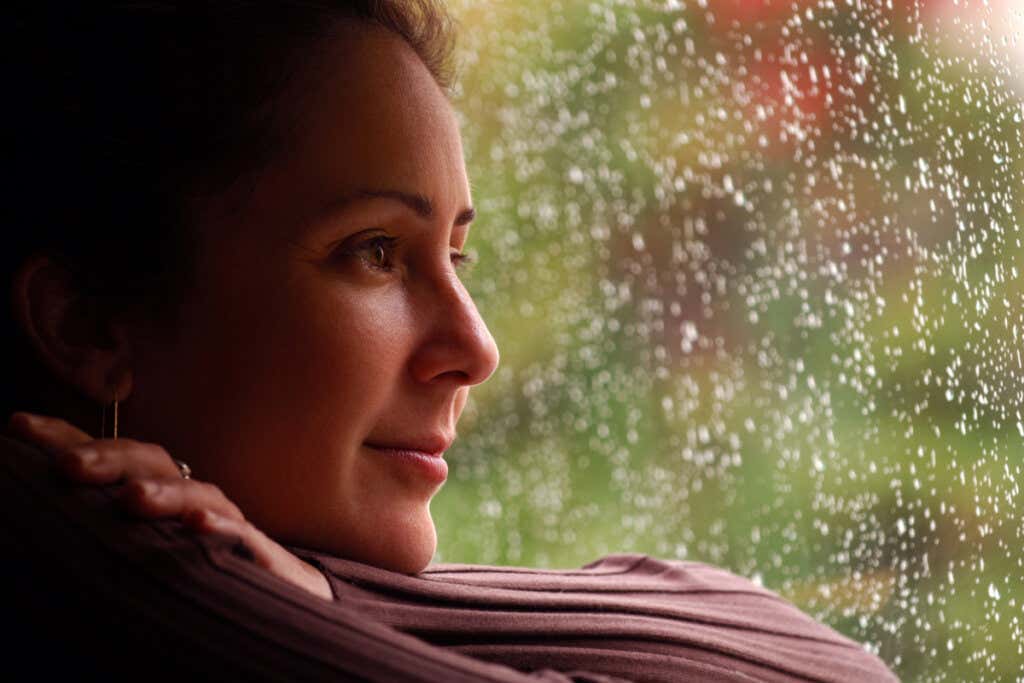 Femme souriante regardant par la fenêtre