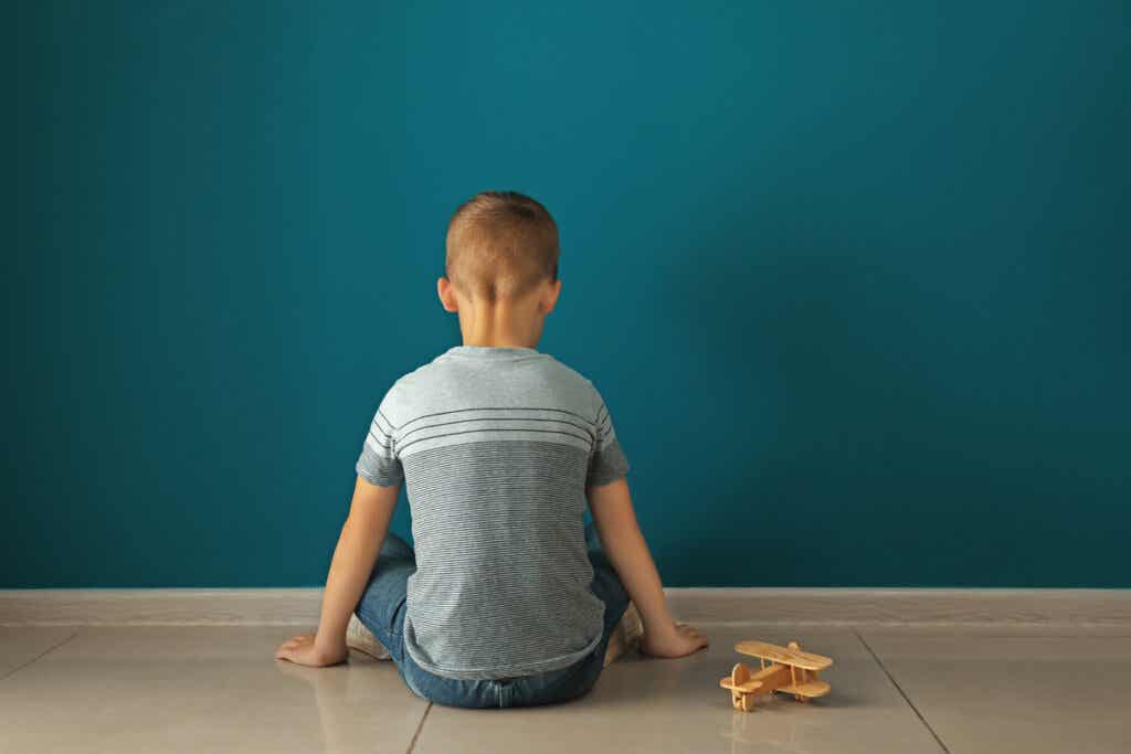 Niño con autismo sentado frente a la pared