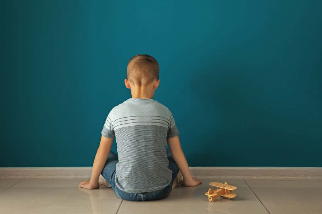 Niño con autismo sentado frente a la pared