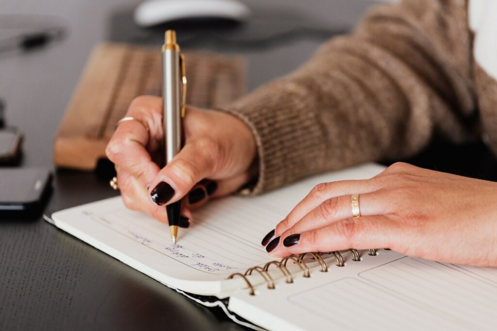 Femme écrivant son plan de croissance personnel dans un cahier.
