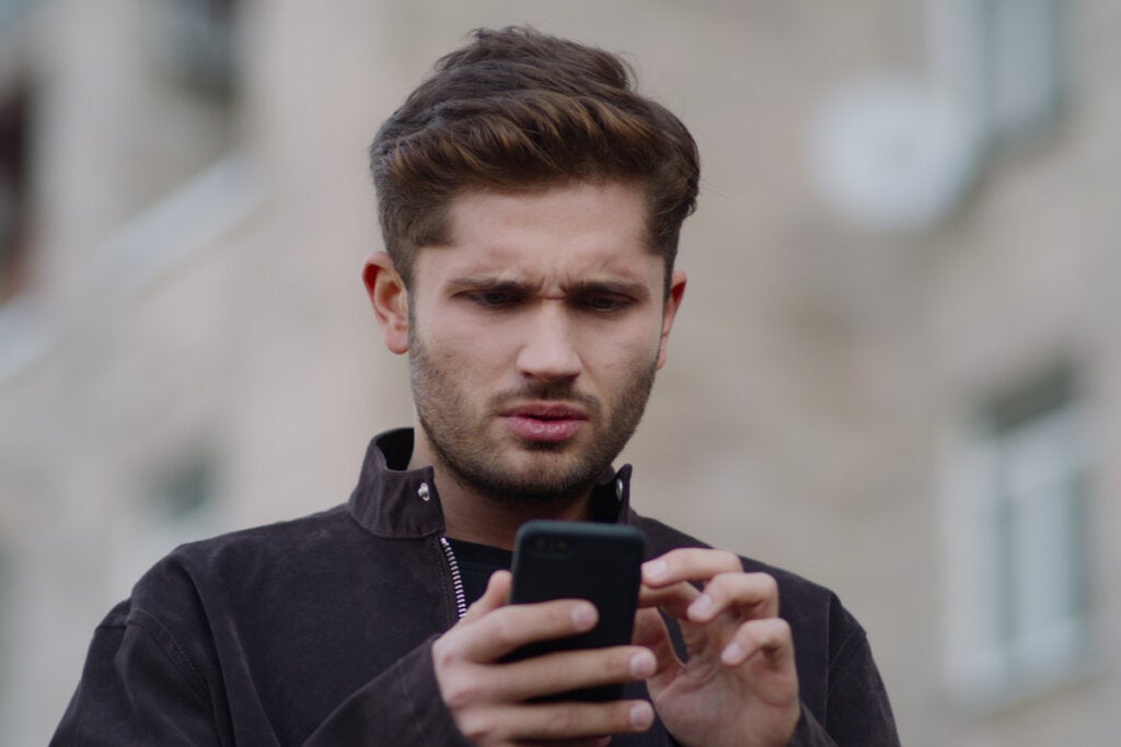 Homem lendo mensagens abusivas no celular