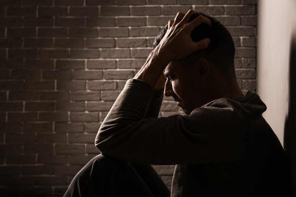 Hombre sentado en el suelo sufriendo vergüenza asociada al abuso emocional