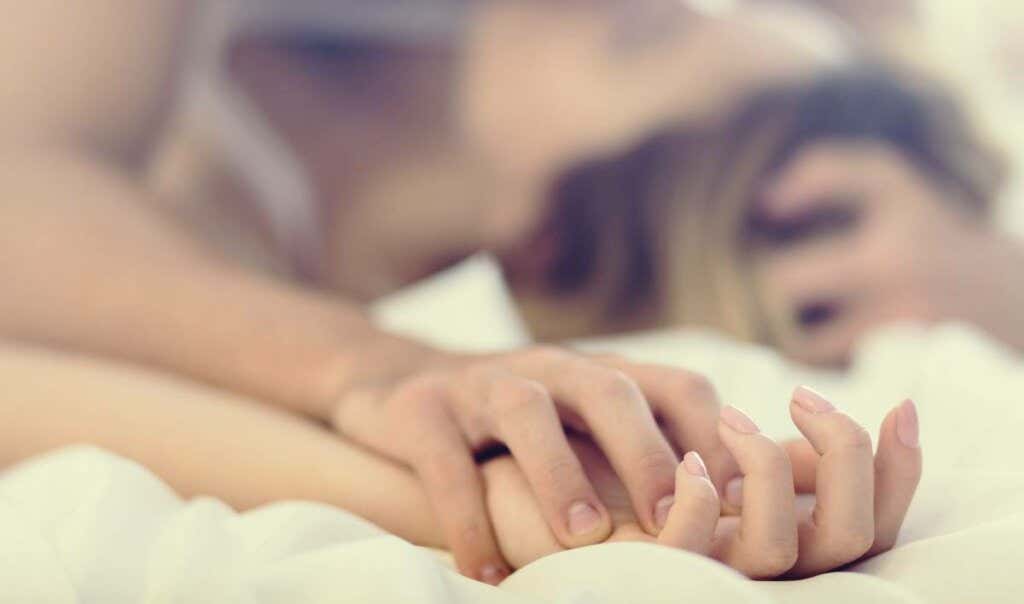 mãos de casal na cama representando o que é desejo erótico