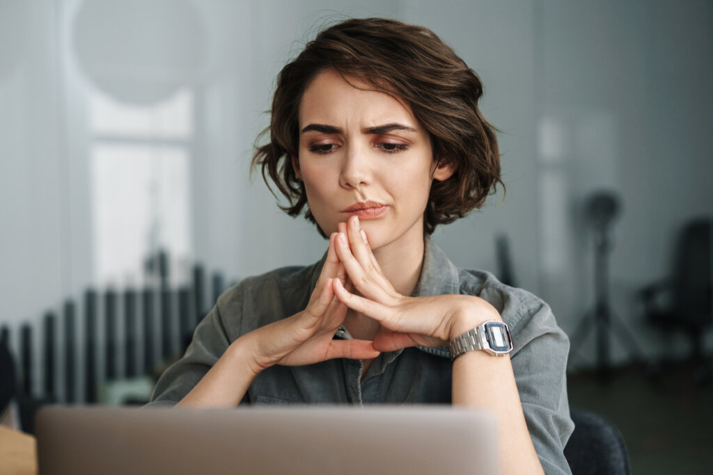 Femme concentrée à l'ordinateur pensant
