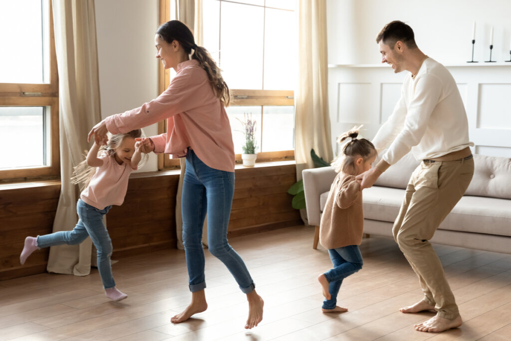 Parents dancing in the living room with their young daughters.