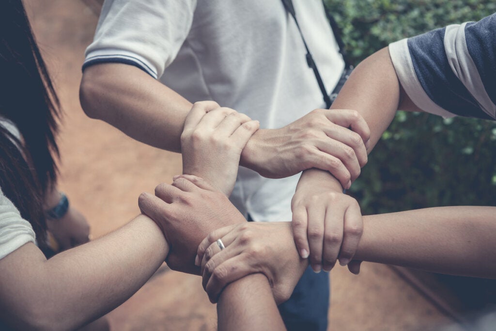 Gruppe mennesker holder hverandres armer for å hjelpe hverandre