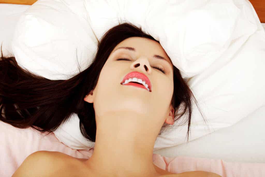 Donna a letto sorridente per l'orgasmo.