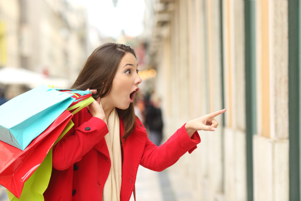 Une femme enthousiaste à l'idée de faire du shopping en pensant pourquoi j'achète des choses dont je n'ai pas besoin ?