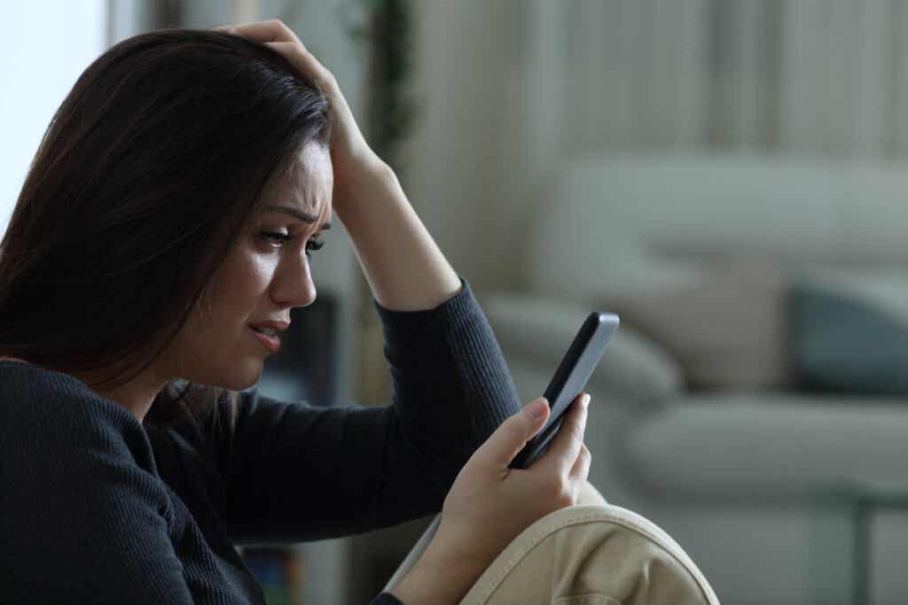 Chica llorando mientras mira el móvil que sufre ansiedad social y nuevas tecnologías