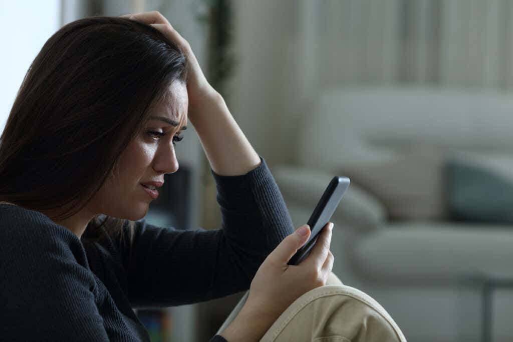Chica llorando mientras mira el móvil pensando en cómo lidiar con los comentarios hirientes