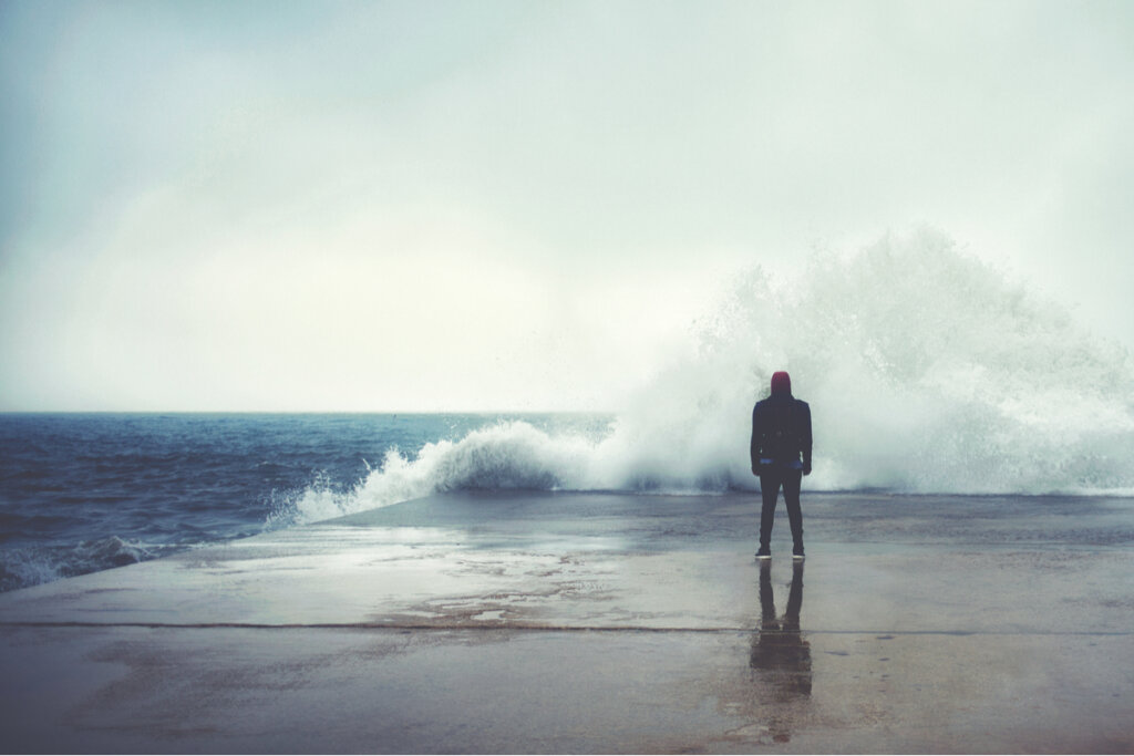 Man facing a wave of the sea suffering from psychasthenia