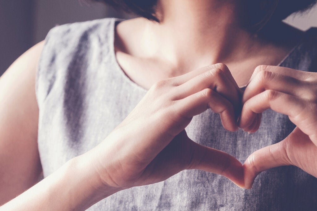 Mujer haciendo un corazón con sus manos representando Por qué cuando estamos tristes nos duele el pecho