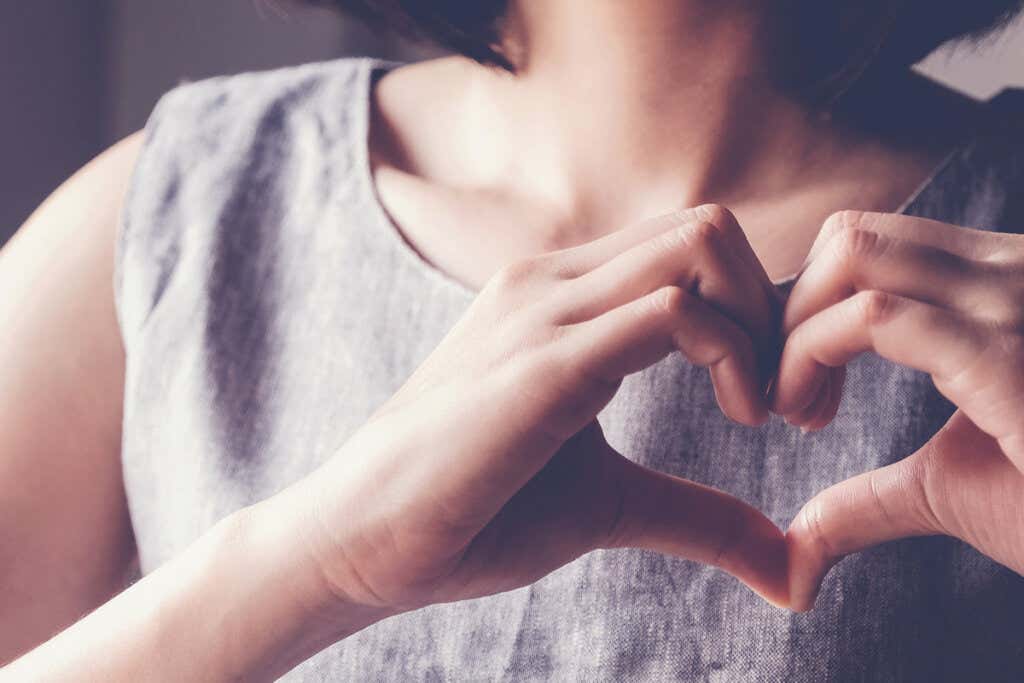 Mujer haciendo un corazón con sus manos como señal de autohonestidad