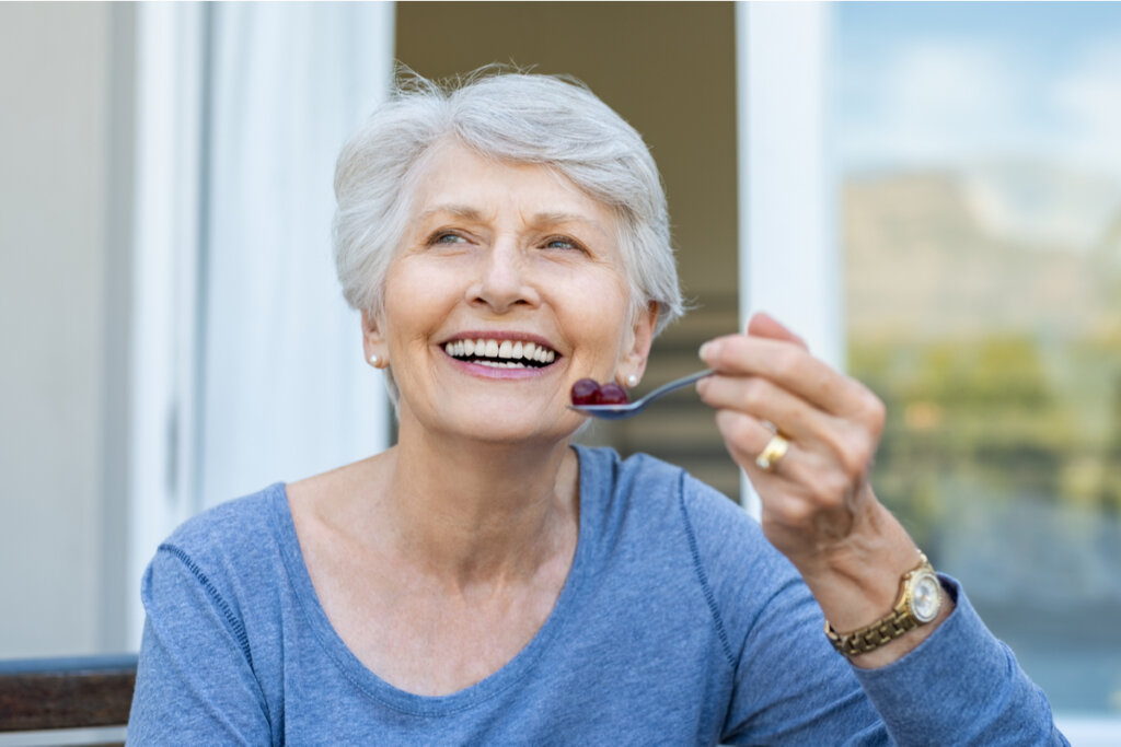 Mujer mayor comiendo uvas rojas