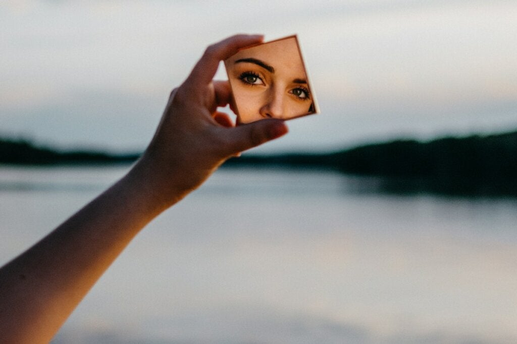 Frau blickt in den Spiegel und denkt an die Vergangenheit, Gegenwart und Zukunft ihres Selbstkonzepts
