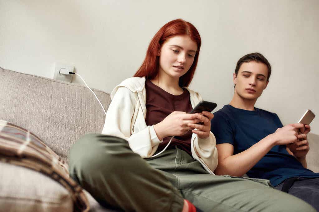 Pareja de adolescentes con móviles representando la relación entre la pornografía online y la violencia sexual