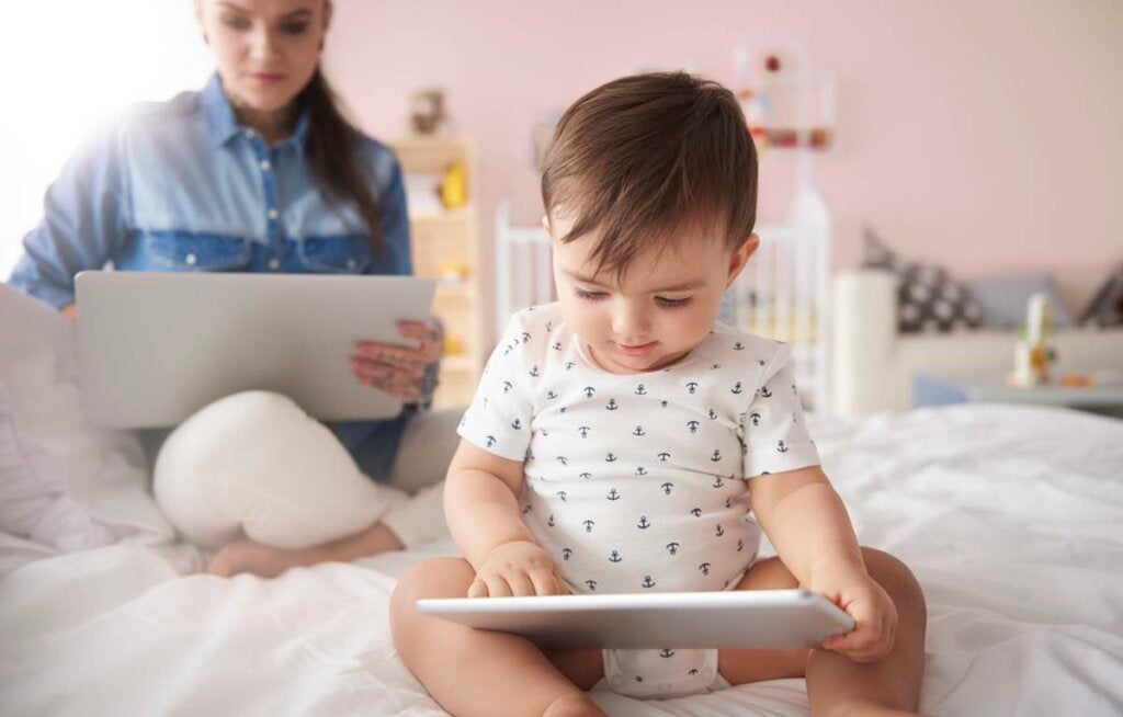 bebé con tablet representando cómo las pantallas aceleran a los niños 