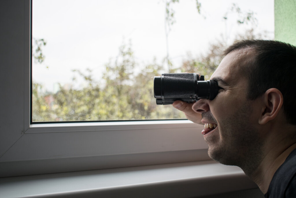 Mann mit Fernglas leidet an pathologischem Voyeurismus