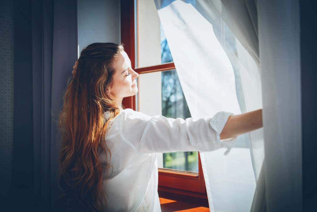 Mulher abrindo uma janela para apreciar a luz azul