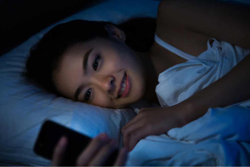 Kobieta w łóżku z telefonem komórkowym