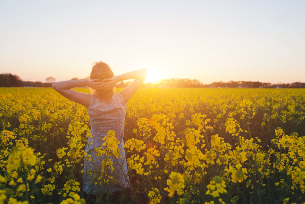 Femme sur le terrain avec des fleurs jaunes pensant à vous pardonner et à surmonter le passé