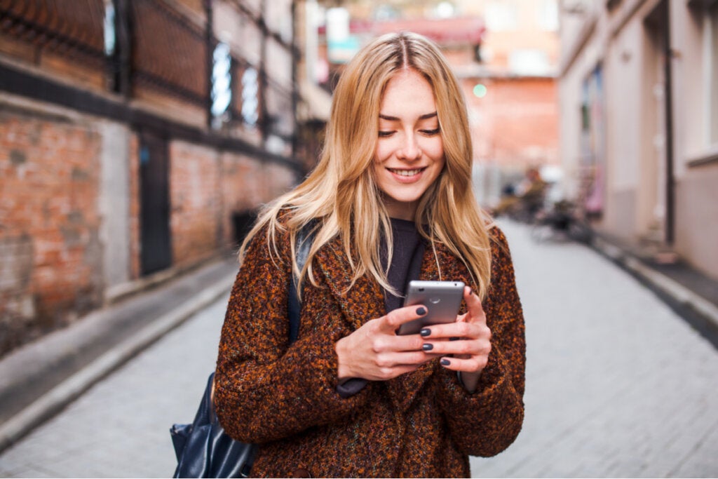 Mujer sonriendo con el móvil hablando con sus amistades pasivas y activas