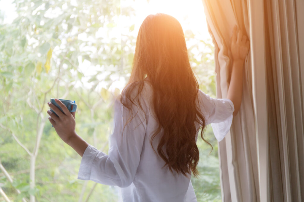 Vrouw drinkt koffie bij het raam