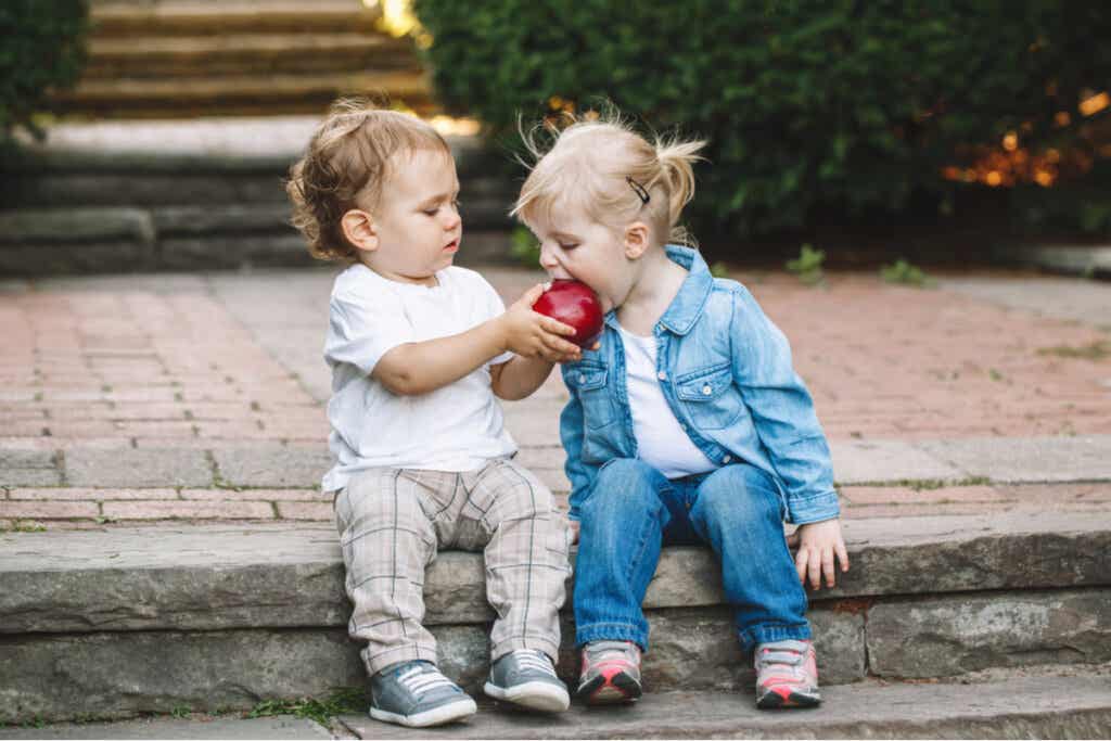 Niño pequeño dando una manzana a otra niña