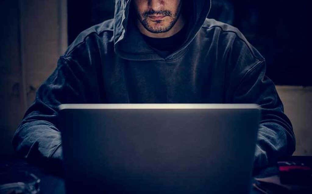 Zakapturzony mężczyzna przy komputerze