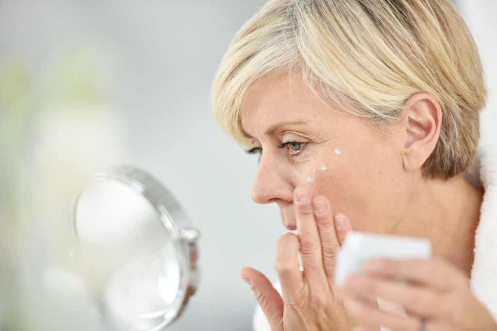 Mujer de mediana edad echándose crema en la cara