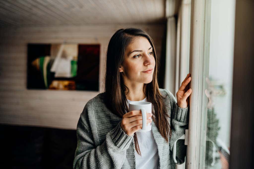 elinde kahvesiyle pencereden dışarıya bakan kadın