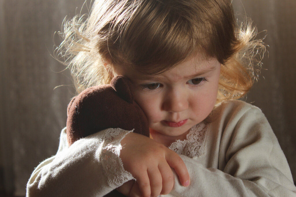 Niña triste abrazada a un peluche