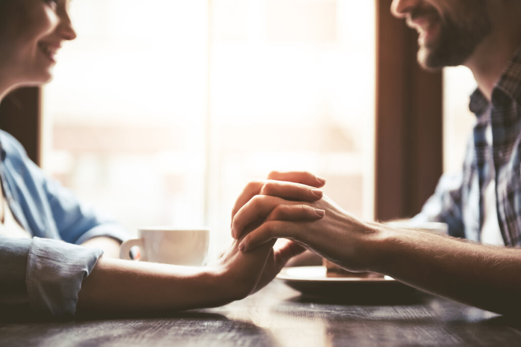 Couple looking at each other holding hands representing how to take the first step with someone you like