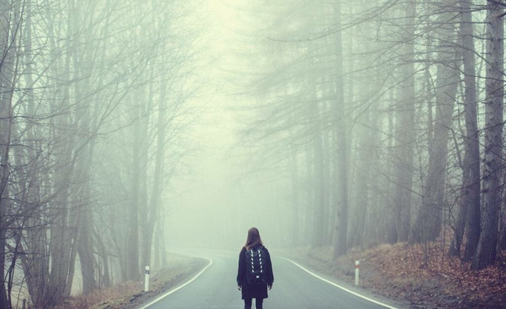 Vrouw loopt op de weg in de mist