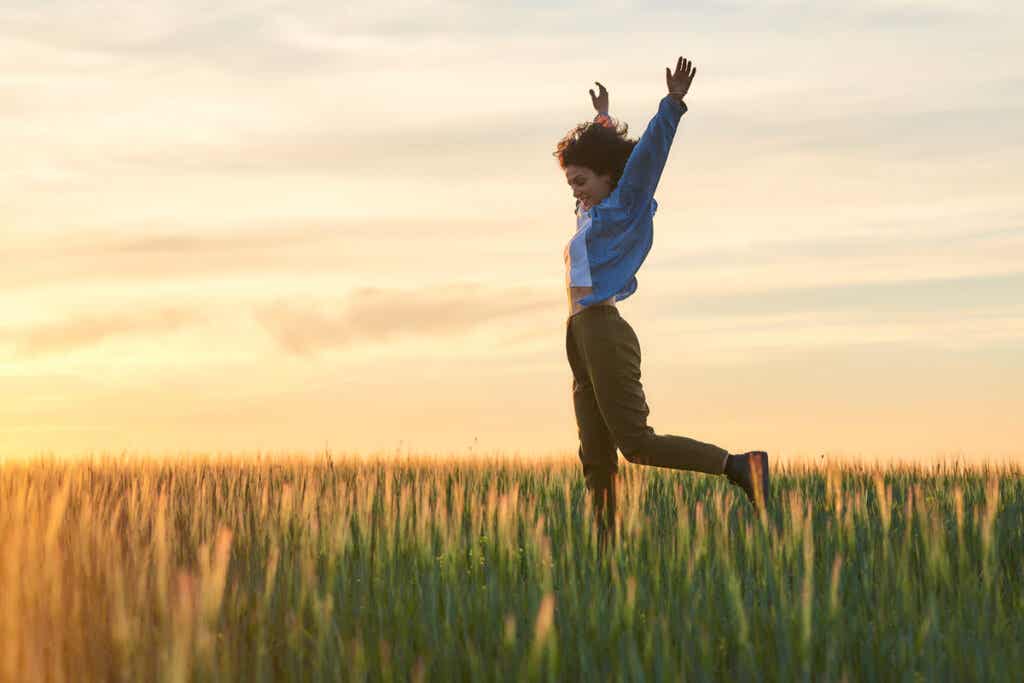 Mujer feliz saltando en el campo representando cómo despertar tu entusiasmo