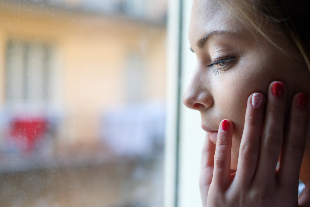Femme inquiète regardant par la fenêtre