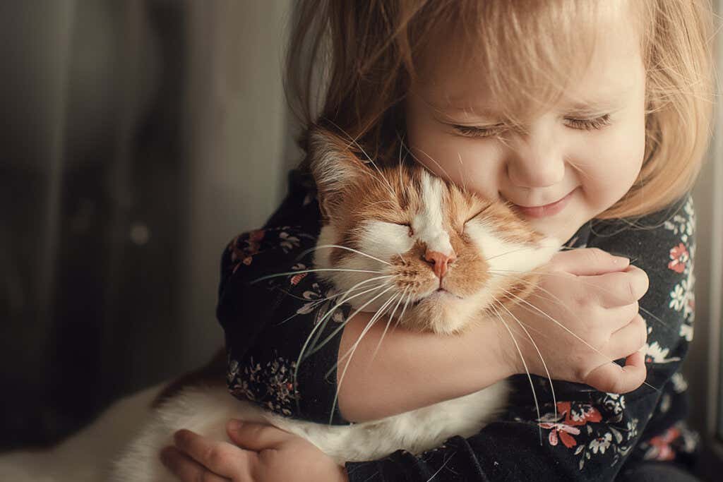 Flicka som kramar en kattunge
