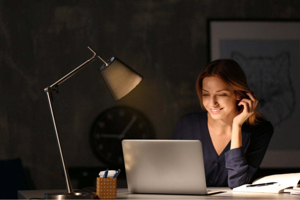 Mulher trabalhando no computador à noite com síndrome de ilegitimidade.