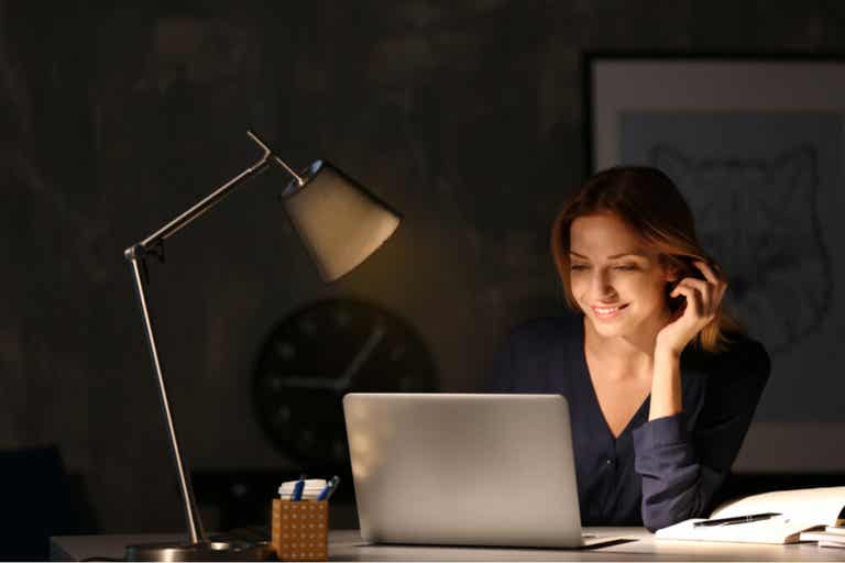 Mulher trabalhando no computador à noite com síndrome de ilegitimidade.