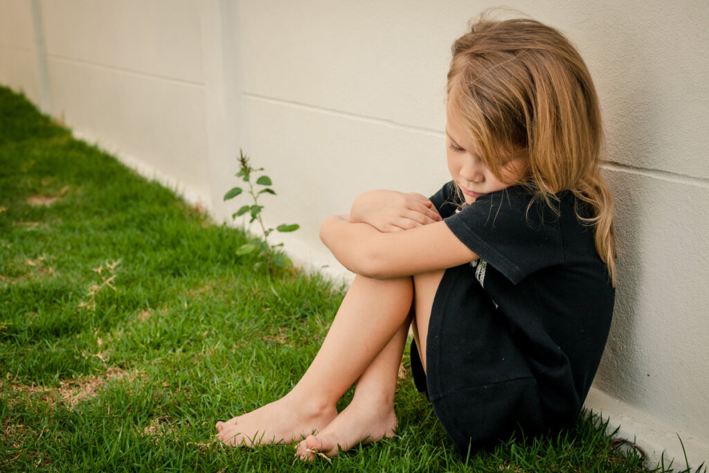 Niña triste sentada en el suelo