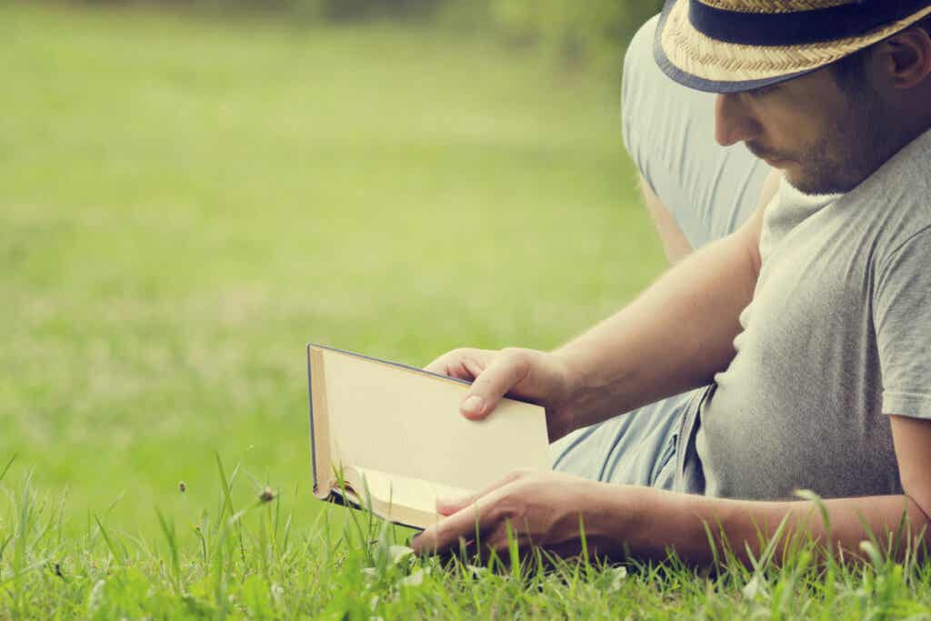 Mann som leser en bok på gresset