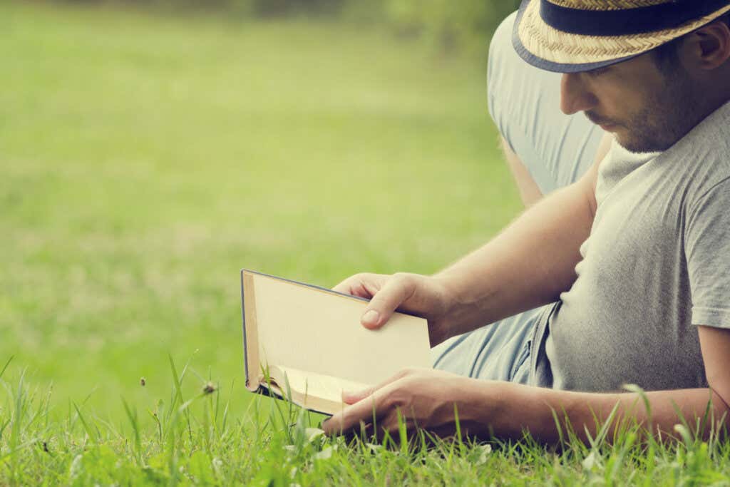 Mies lukee kirjaa ruoholla