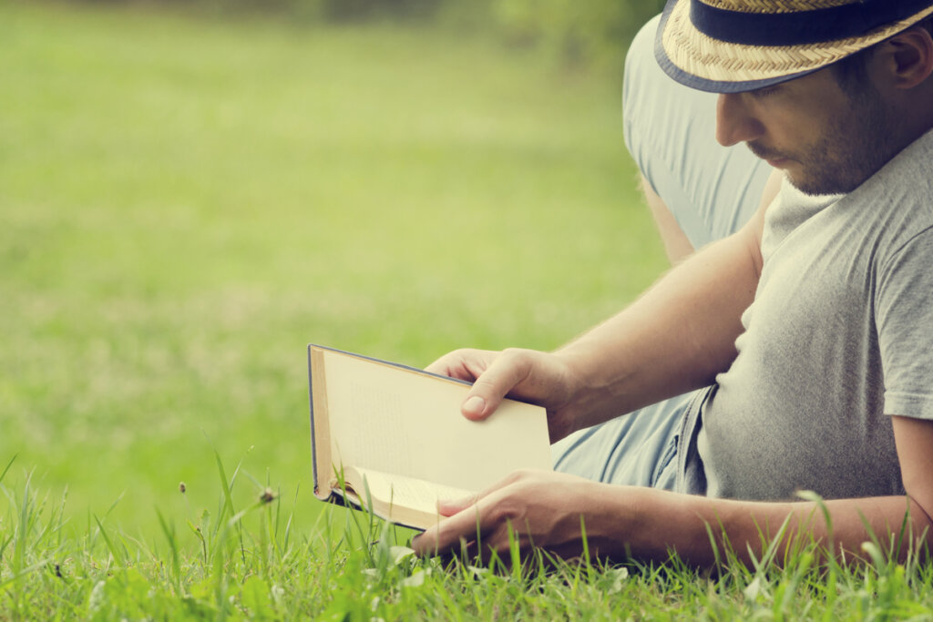 Hombre leyendo un libro en el césped