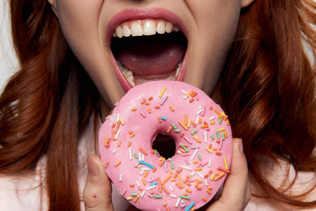 Mulher comendo donut cheio de açúcar