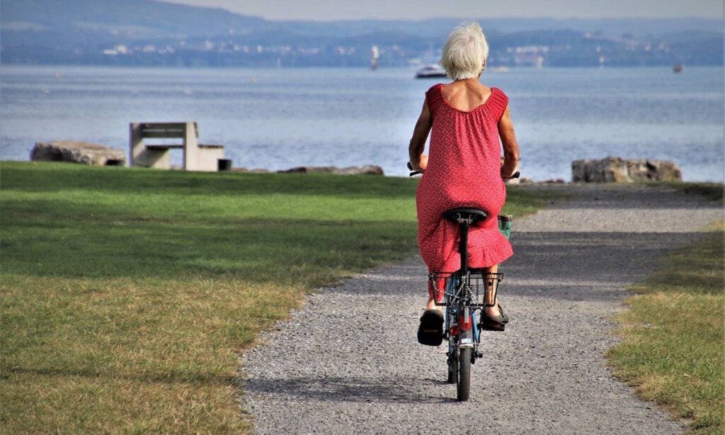 Mujer mayor en una bicicleta representando a las personas que florecen a la tercera edad